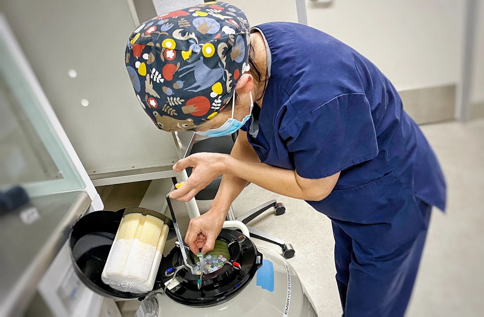 Embryologist taking tube from liquid nitrogen cryogenic tank.